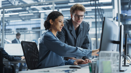 Poster - Caucasian Man and Hispanic Woman Having Conversation at Industrial Facility. Employees Working Together, Using Desktop Computer for Supervising Work Process in Automated Factory With Robotic Arms.