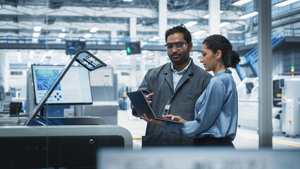 Fototapete - Indian Male Industrial Engineer And Hispanic Female Supervisor Using Laptop And Talking At Electronics Factory. Man Using Soldering Jet Printer, Explaining Process Behind Production Of Motherboards.