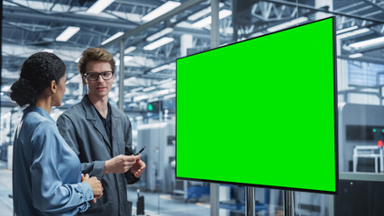 Aufkleber - Meeting In Office Of Autonomous Factory With Robotic Arms: Hispanic Female Engineer Talking with Caucasian Male Assembly Line Supervisor And Using TV With Green Screen Chromakey On Display.