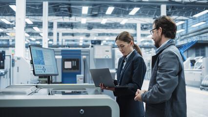 Leinwandbilder - Male Technician and Female Businesswoman Using Laptop In Modern Electronics Factory. Caucasian Man Explaining Production Of Motherboards For AI Powered Devices With Soldering Jet Printer.