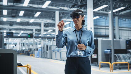 Fototapete - Hispanic Female Engineer Wearing an Augmented Reality Headset And Controlling Autonomous Production At an Electronics Factory. Woman Using Gestures To Configure Assembly Line of High-Tech Devices