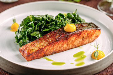 Wall Mural - Portion of salmon steak with spinach on restaurant served table