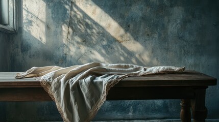 Poster - Elegant linen tablecloth draped on a rustic wooden table in a softly lit vintage setting with textured walls and natural shadows.
