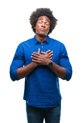 Wall Mural - afro american man over isolated background smiling with hands on chest with closed eyes and grateful