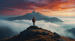 © demzp - Mountains loom under a vivid sunset as a hiker admires the view