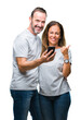 © Krakenimages.com - Middle age hispanic couple texting message on smartphone ver isolated background happy with big smile doing ok sign, thumb up with fingers, excellent sign