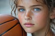 © Ева Поликарпова - A young girl holds a basketball in front of her face, ready for action