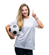 © Krakenimages.com - Young beautiful blonde woman holding soccer ball over isolated background surprised with an idea or question pointing finger with happy face, number one
