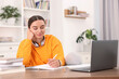 © New Africa - Student with headphones studying at table indoors