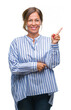 © Krakenimages.com - Middle age senior hispanic woman over isolated background with a big smile on face, pointing with hand and finger to the side looking at the camera.