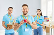 © Studio Romantic - Portrait of a volunteer holding a red heart surrounded by a team in a humanitarian aid center. Charity, teamwork, and community support within a donation organization dedicated to helping others.