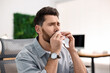 © New Africa - Sick man with runny nose in office