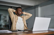 © insta_photos - Happy young African business man feeling relaxed enjoying good work results looking at laptop in office. Smiling professional businessman entrepreneur finished computer work at workplace.