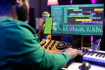 Poster - Producer using stereo console to apply mixing and mastering techniques, having a copyspace display on his phone. Artist songwriter producing new soundtracks in home studio.