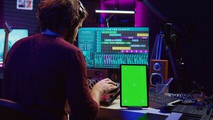 Poster - Music producer songwriter mixing tunes on stereo console, recording sounds next to tablet with greenscreen layout. Artist using equalizer and control panel board, daw software. Camera B.