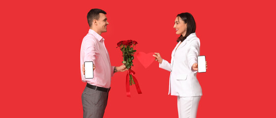 Wall Mural - Young couple with mobile phones, bouquet of roses and paper heart on red background. Online dating