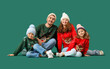 © Pixel-Shot - Happy family in warm sweaters sitting on green background