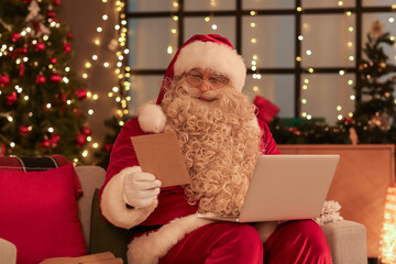 Wall Mural - Santa Claus with laptop and letter at home on Christmas eve