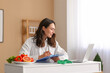 © Pixel-Shot - Young female nutritionist with clipboard and laptop working at table in office