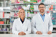 © peopleimages.com - Portrait, man and woman in pharmacy with smile, healthcare and professional service in medicine store. Health insurance, drugs and pharmacist team in dispensary for medical advice, support and help