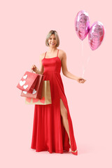 Wall Mural - Beautiful woman with shopping bags and balloons on pink background. Valentine's Day celebration