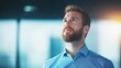 © nattapon98 - A thoughtful man gazes upward, reflecting in a modern office environment with soft lighting and a blurred background.