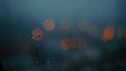 Wall Mural - Close-up of rain droplets trickling down a city window during a gloomy evening
