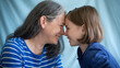 ©  Mohammad Xte - Happy Mother and Daughter in Affectionate Pose, Noses Touching in Intimate Bonding Moment, Soft Studio Blue Background, Warm Connection, Loving Family Portrait, Close and Tender Interaction