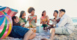 © peopleimages.com - People, friends and watermelon at beach, picnic and conversation with eating, vacation and reunion. Group, women and men with fruit, happy and outdoor together with diversity by ocean in sunshine