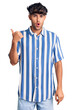 © Krakenimages.com - Young hispanic man wearing casual clothes surprised pointing with hand finger to the side, open mouth amazed expression.