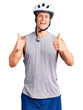© Krakenimages.com - Young handsome man wearing bike helmet success sign doing positive gesture with hand, thumbs up smiling and happy. cheerful expression and winner gesture.