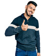 © Krakenimages.com - Young hispanic man with beard wearing casual winter sweater doing happy thumbs up gesture with hand. approving expression looking at the camera showing success.
