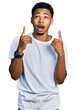 © Krakenimages.com - Young african american man wearing casual white t shirt amazed and surprised looking up and pointing with fingers and raised arms.