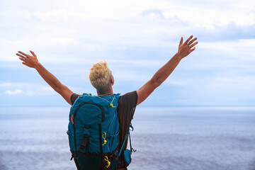Wall Mural - happy tourist man with backpack enjoying freedom and travel. wellbeing, journey and tourism concept