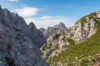 © Chris - Hiking trail with scenic view of rugged mountain peak Razor in Julian Alps seen from Triglav National Park, Vrsic pass, Slovenia. Wanderlust wild Slovenian Alps. Sharp steep ridges in alpine terrain