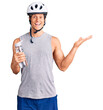 © Krakenimages.com - Young handsome man wearing bike helmet holding bottle of water celebrating victory with happy smile and winner expression with raised hands