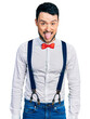 © Krakenimages.com - Hispanic man with beard wearing hipster look with bow tie and suspenders sticking tongue out happy with funny expression. emotion concept.