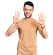 © Krakenimages.com - Hispanic man with beard wearing casual t shirt showing and pointing up with fingers number nine while smiling confident and happy.