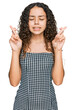 © Krakenimages.com - Teenager hispanic girl wearing casual clothes gesturing finger crossed smiling with hope and eyes closed. luck and superstitious concept.