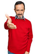 © Krakenimages.com - Middle age hispanic man wearing casual clothes smiling friendly offering handshake as greeting and welcoming. successful business.