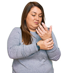 Wall Mural - Beautiful brunette plus size woman wearing casual clothes suffering pain on hands and fingers, arthritis inflammation