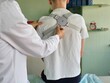© Nadzeya - Medical specialist adjusts therapeutic device on patient's back during treatment session
