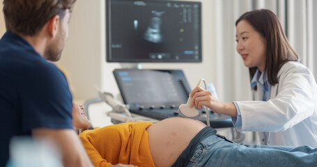 Aufkleber - Asian Obstetrician Conducts Prenatal Ultrasound for Smiling Expectant Mother in Yellow Top. Husband Observes as Doctor Explains Fetal Development Using Advanced Imaging Technology in Modern Hospital