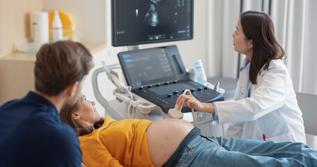Aufkleber - Asian Obstetrician Performs Ultrasound on Pregnant Patient, Explaining Baby Development. Modern Medical Equipment Displays Detailed Sonogram Images as Doctor Gestures Towards Screen