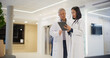 © Gorodenkoff - Caucasian Doctor and Young Asian Female Physician Discuss Patient Data on Tablet in Modern Hospital Lobby. Having a Casual Healthcare Conversation and Discussing Online Medical Data