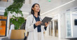 © Gorodenkoff - Asian Female Doctor Standing in a Bright Hospital Reception Hall, Focused on Reviewing Patient Online Records on Her Tablet Computer and Deciding on Correct Medical Prescription