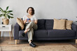 © LIGHTFIELD STUDIOS - A beautiful young woman relaxes on a couch, sipping a warm drink in her stylish space.