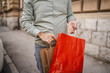 © Miljan Živković - close up of mature man hands hold red and beige shopping bags outdoor