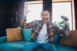 © deagreez - Happy young man enjoying leisure time at home in stylish plaid shirt in cozy apartment