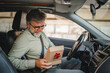 © Miljan Živković - Senior mature man sit in the car and hold small gift with red ribbon